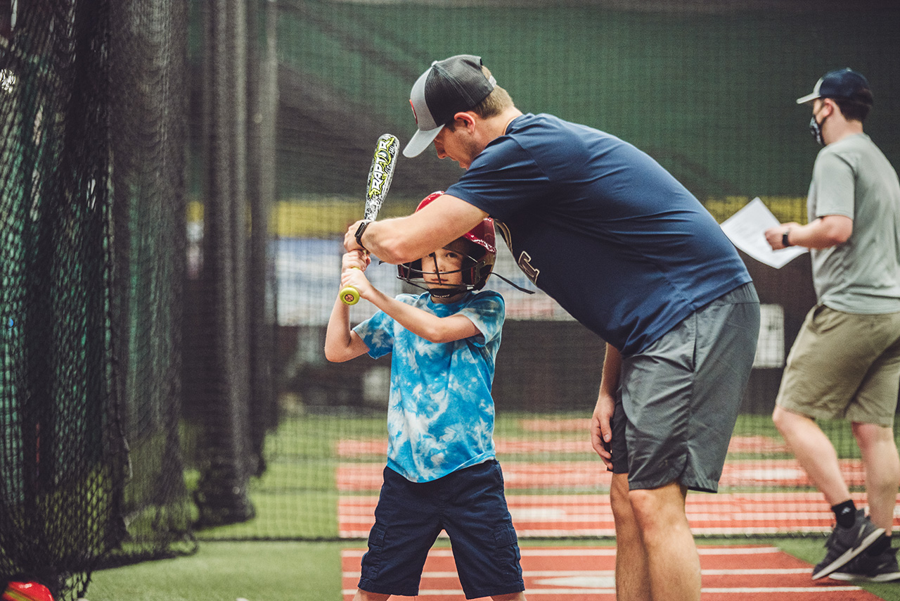 A boy with a bat and his baseball coach